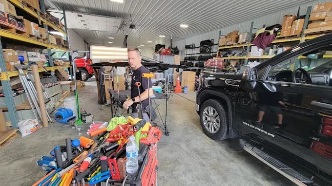 PDR technician working beside a mobile tool cart inside the Mike's Service Center repair bay